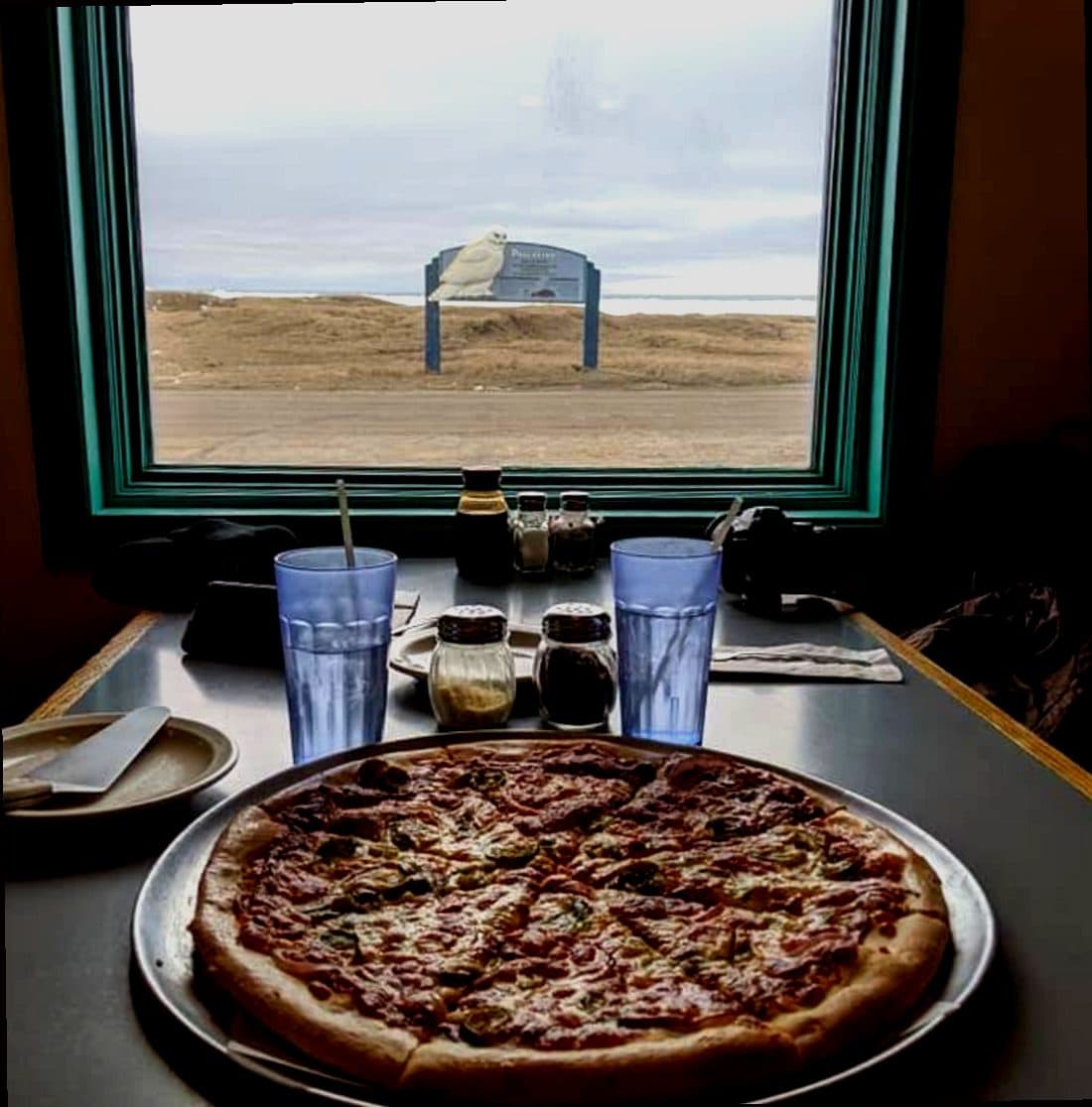 Fresh pizza at Mario's Pizza with Arctic landscape view through window